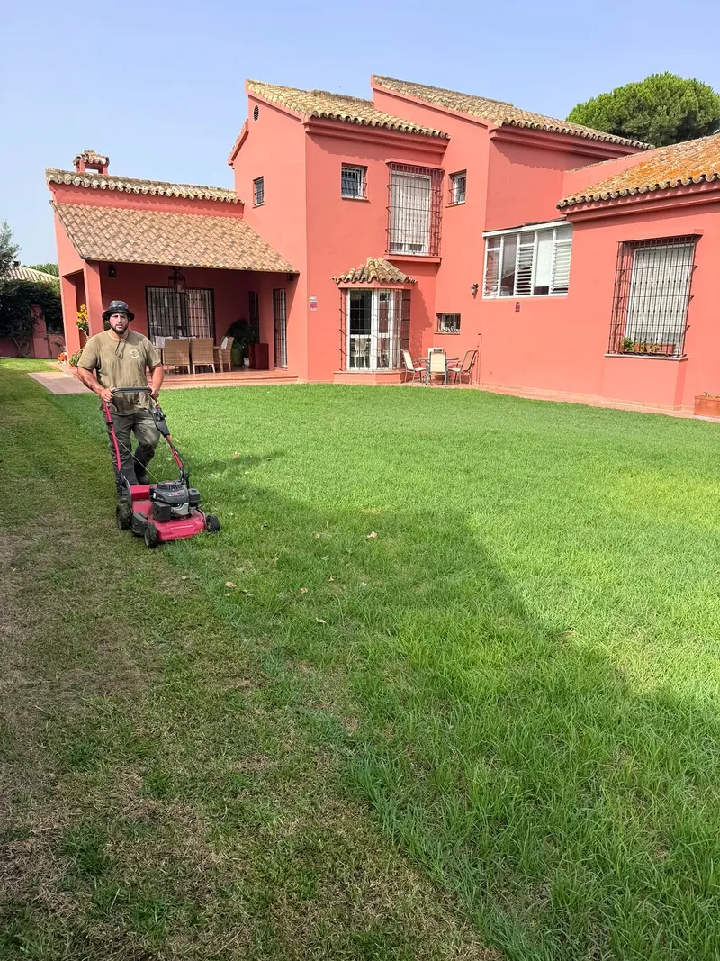 Alfonso segando y perfilando el césped de un jardín en El Puerto de Santa María