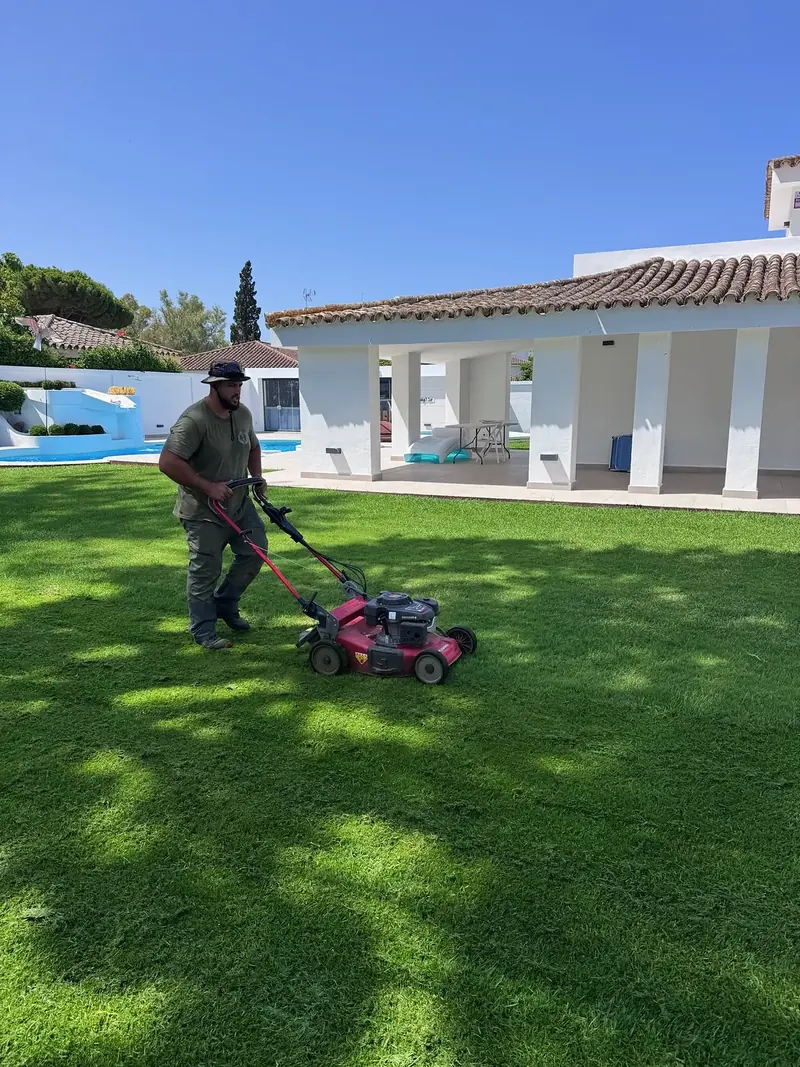 Alfonso segando el césped de un chalet con piscina en El Puerto de Santa María